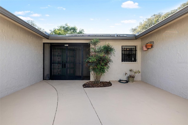 view of exterior entry with a patio area and stucco siding