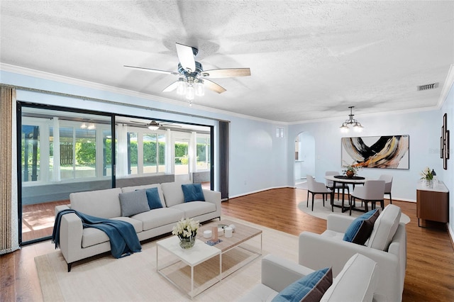 living room featuring wood finished floors, arched walkways, and a textured ceiling
