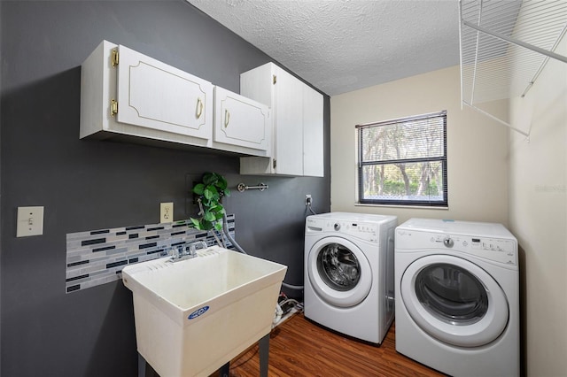 laundry area with a sink, a textured ceiling, washer and dryer, cabinet space, and dark wood-style floors