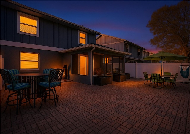 16819 Stanza Ct, Tampa, FL 33624 - patio terrace at dusk featuring a sunroom, outdoor dining space, and fence