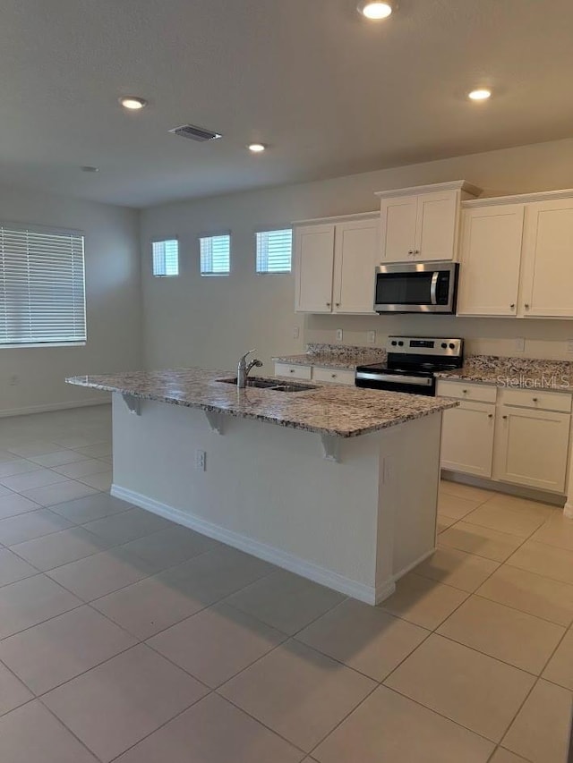 7937 Wheat Stone Dr, Zephyrhills, FL 33540 - kitchen with appliances with stainless steel finishes, a sink, light stone countertops, recessed lighting, and white cabinetry