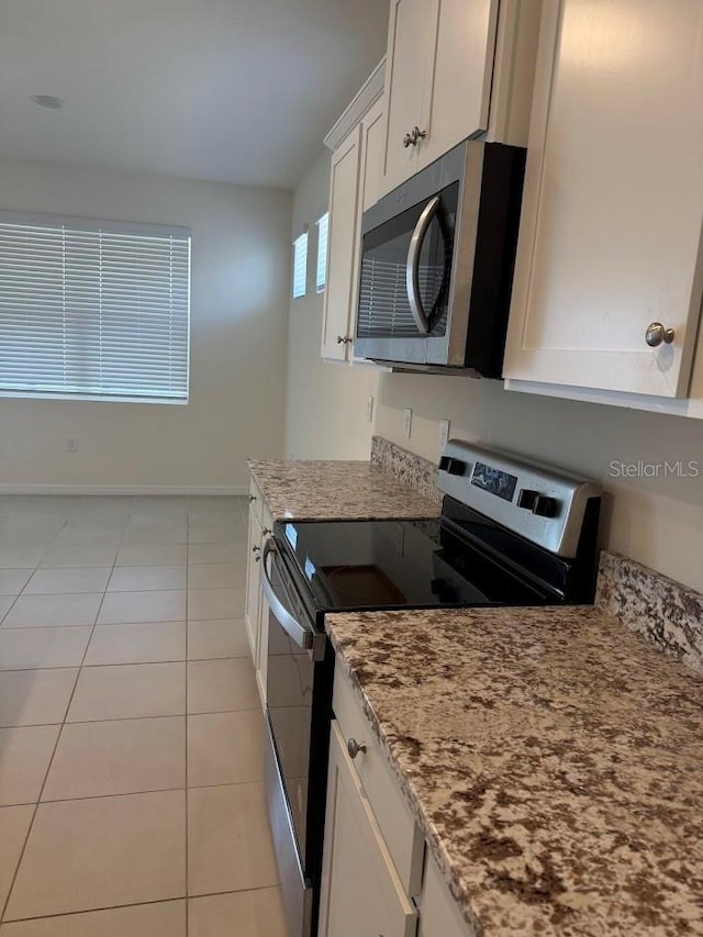 7937 Wheat Stone Dr, Zephyrhills, FL 33540 - kitchen with appliances with stainless steel finishes, light stone counters, white cabinets, light tile patterned flooring, and baseboards