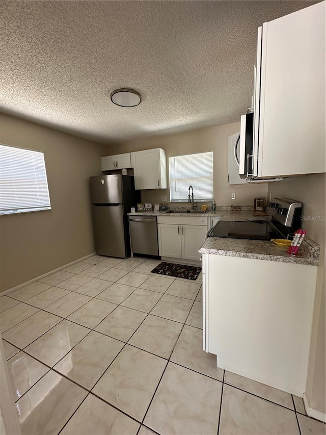 7601 Como Dr, New Port Richey, FL 34655 - kitchen with a sink, light tile patterned flooring, a textured ceiling, appliances with stainless steel finishes, and white cabinetry