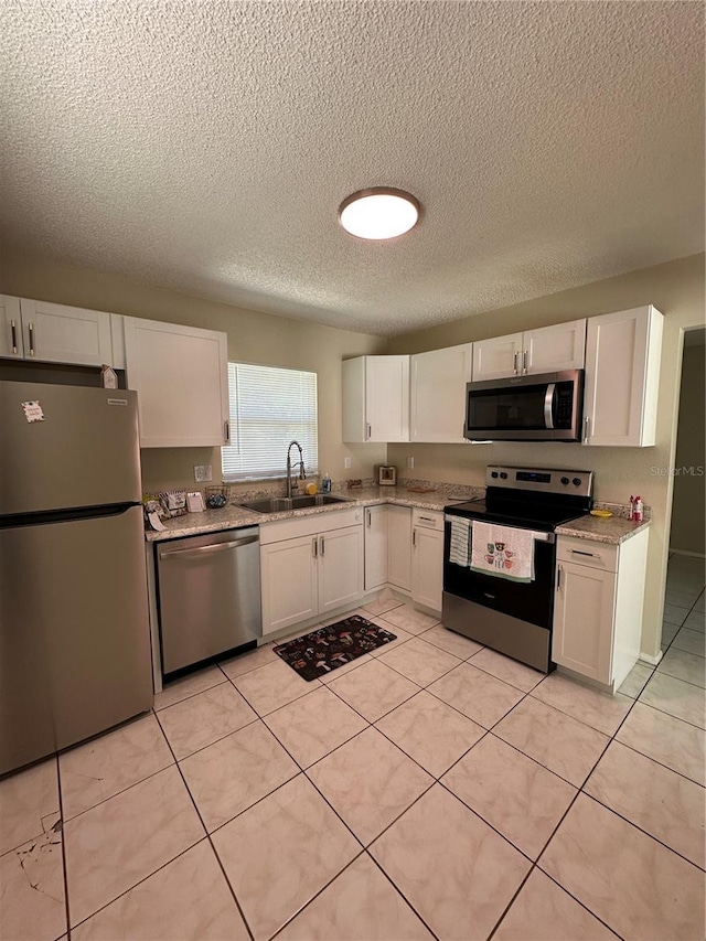 7601 Como Dr, New Port Richey, FL 34655 - kitchen with stainless steel appliances, a textured ceiling, a sink, white cabinetry, and light stone countertops