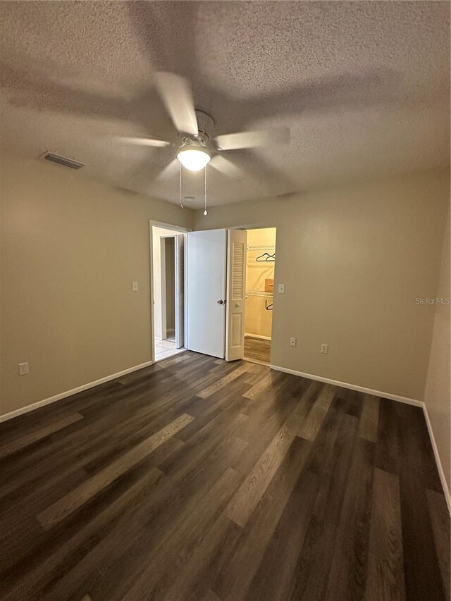 7601 Como Dr, New Port Richey, FL 34655 - unfurnished bedroom featuring a ceiling fan, a textured ceiling, baseboards, dark wood-type flooring, and visible vents