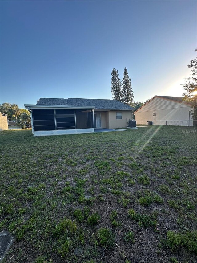 7601 Como Dr, New Port Richey, FL 34655 - back of house featuring central air condition unit, a sunroom, and a lawn