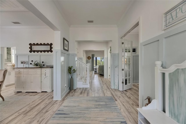 interior space with light wood-style floors, visible vents, crown molding, and stairs
