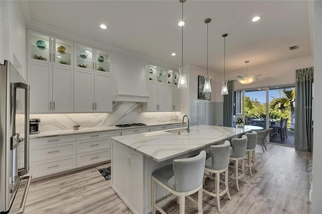 kitchen with light stone countertops, visible vents, a sink, and white cabinetry