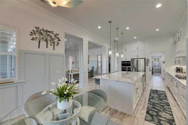kitchen with white cabinets, a decorative wall, ornamental molding, and stainless steel appliances