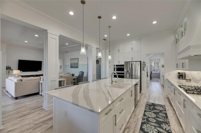 kitchen featuring white cabinets, a sink, light wood-style floors, and appliances with stainless steel finishes