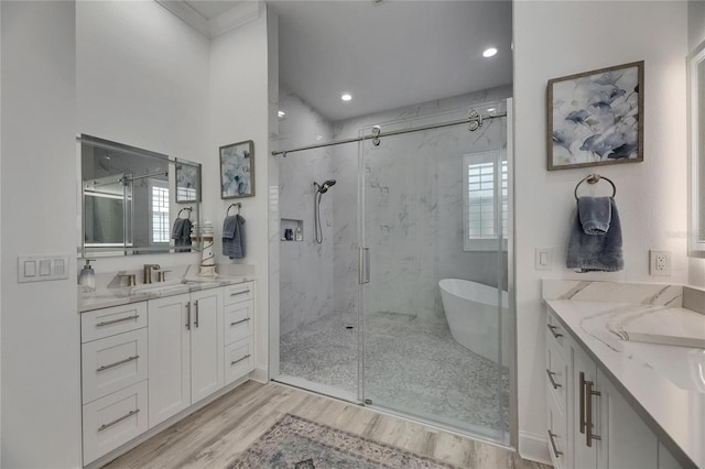 full bath with a marble finish shower, two vanities, a sink, recessed lighting, and wood finished floors
