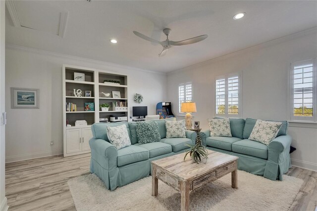 living room featuring crown molding, light wood-style flooring, a ceiling fan, and plenty of natural light