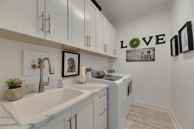 laundry room with a sink, separate washer and dryer, light wood-type flooring, cabinet space, and baseboards