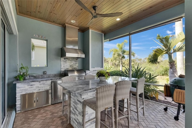 kitchen with brick floor, wall chimney exhaust hood, crown molding, fridge, and ceiling fan