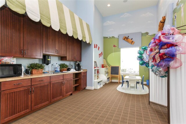 5026 Barnet Dr, Davenport, FL 33837 - kitchen with light countertops, light carpet, a sink, black microwave, and baseboards