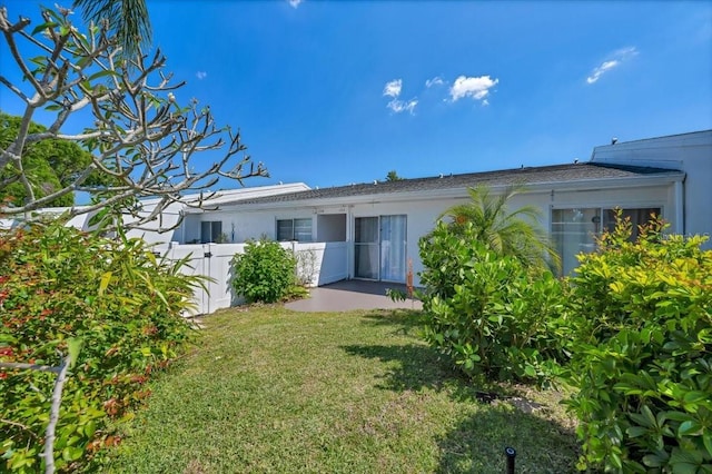 back of property with stucco siding, a patio area, a lawn, and fence