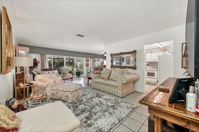 living room with ceiling fan, visible vents, and light tile patterned floors