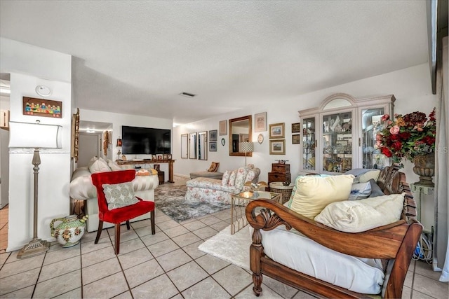 living area with visible vents, a textured ceiling, and light tile patterned floors