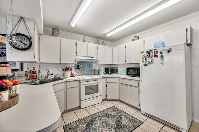 kitchen with a sink, white appliances, light tile patterned floors, light countertops, and under cabinet range hood