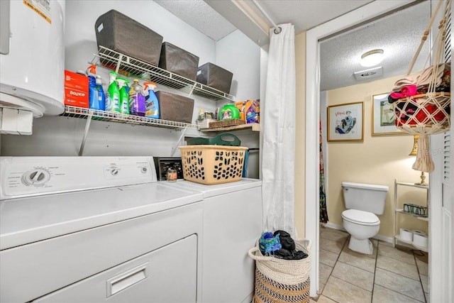 laundry area featuring washing machine and clothes dryer, light tile patterned flooring, a textured ceiling, and laundry area