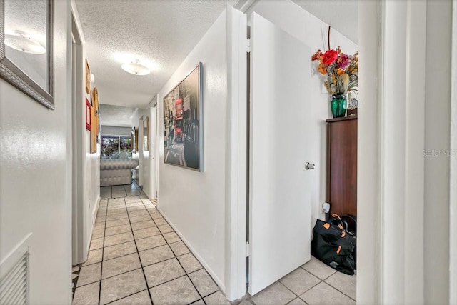 hall featuring light tile patterned flooring and a textured ceiling