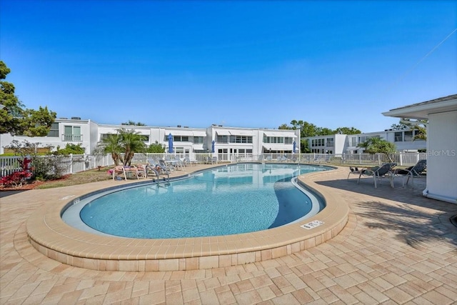 community pool with fence and a patio area