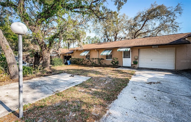 618 July Dr, Tarpon Springs, FL 34689 - ranch-style house featuring stucco siding, an attached garage, and driveway