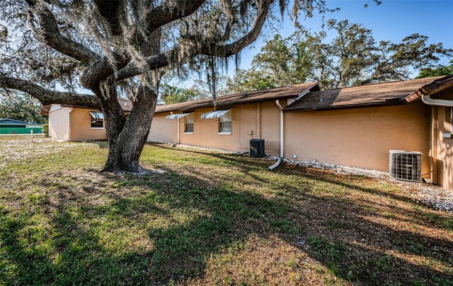 618 July Dr, Tarpon Springs, FL 34689 - view of side of property with stucco siding, central AC unit, and a lawn