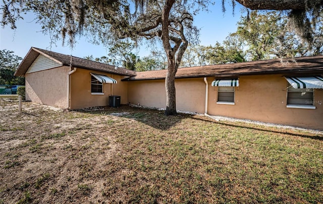 618 July Dr, Tarpon Springs, FL 34689 - rear view of house with a lawn, cooling unit, and stucco siding