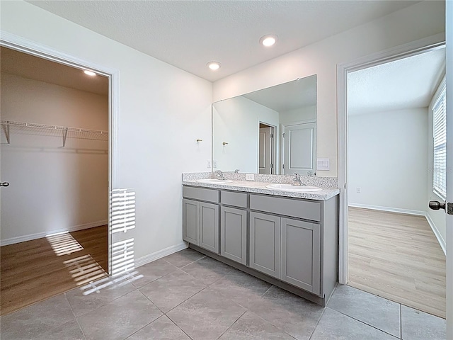 full bath featuring baseboards, a sink, recessed lighting, and double vanity