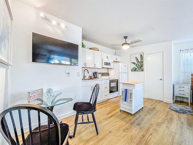1600 Pasadena Dr, Dunedin, FL 34698 - kitchen featuring white appliances, a sink, light wood-style floors, white cabinets, and wood counters