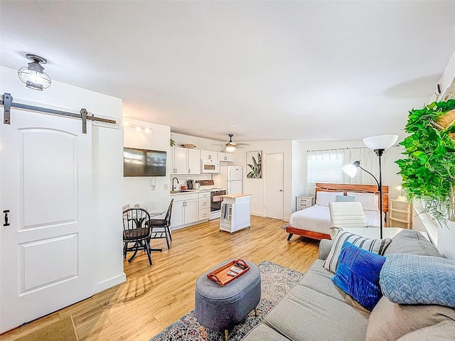 1600 Pasadena Dr, Dunedin, FL 34698 - living room featuring a barn door, light wood-style floors, and ceiling fan