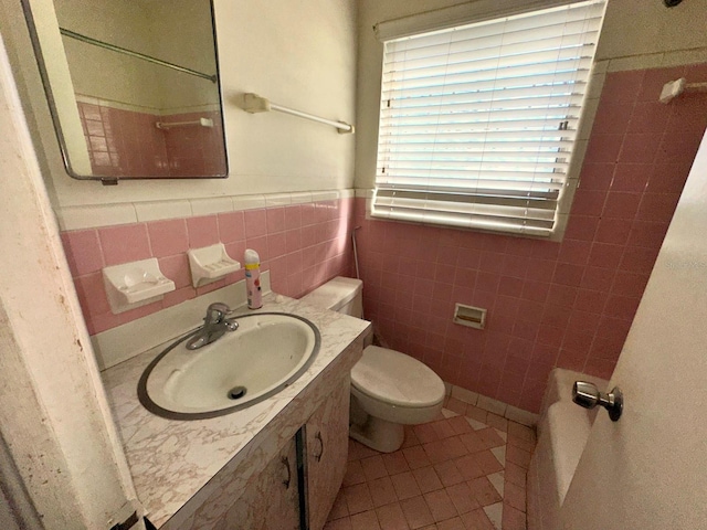 318 Banana St, Tarpon Springs, FL 34689 - bathroom featuring a sink, tile walls, toilet, a wainscoted wall, and tile patterned floors