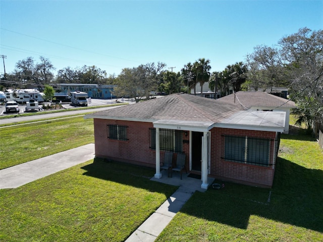 318 Banana St, Tarpon Springs, FL 34689 - view of front of house with a front lawn, brick siding, and roof with shingles