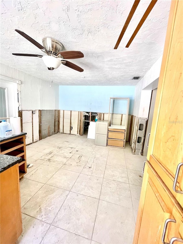 empty room with a textured ceiling, visible vents, and ceiling fan