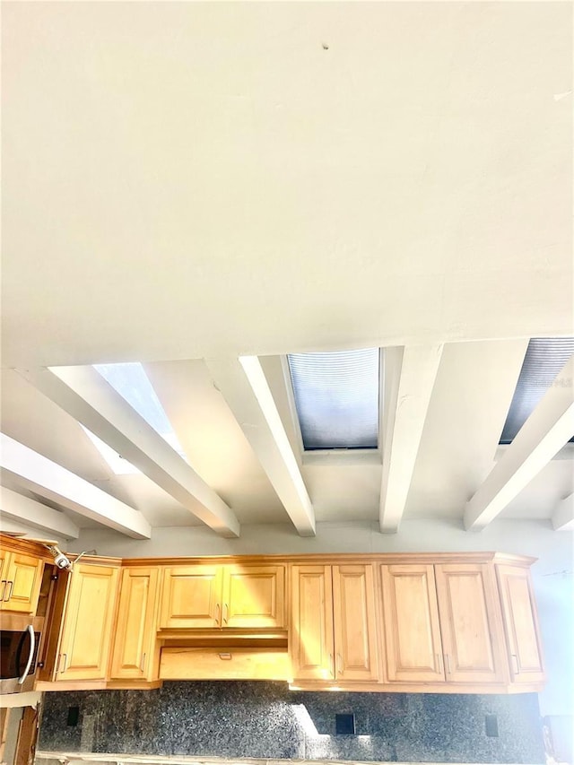 room details featuring stainless steel microwave, light brown cabinetry, and beam ceiling