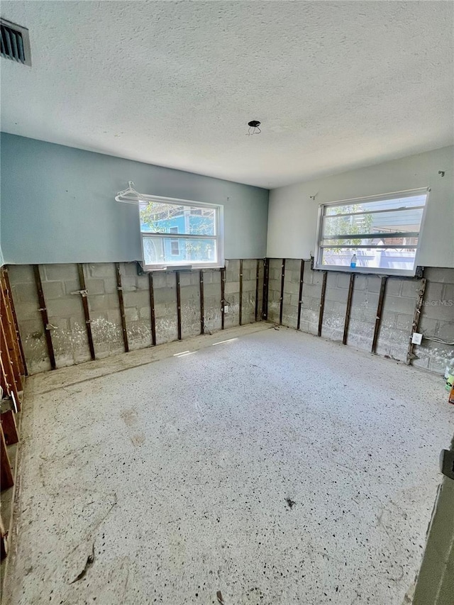 unfurnished room featuring plenty of natural light, visible vents, and a textured ceiling