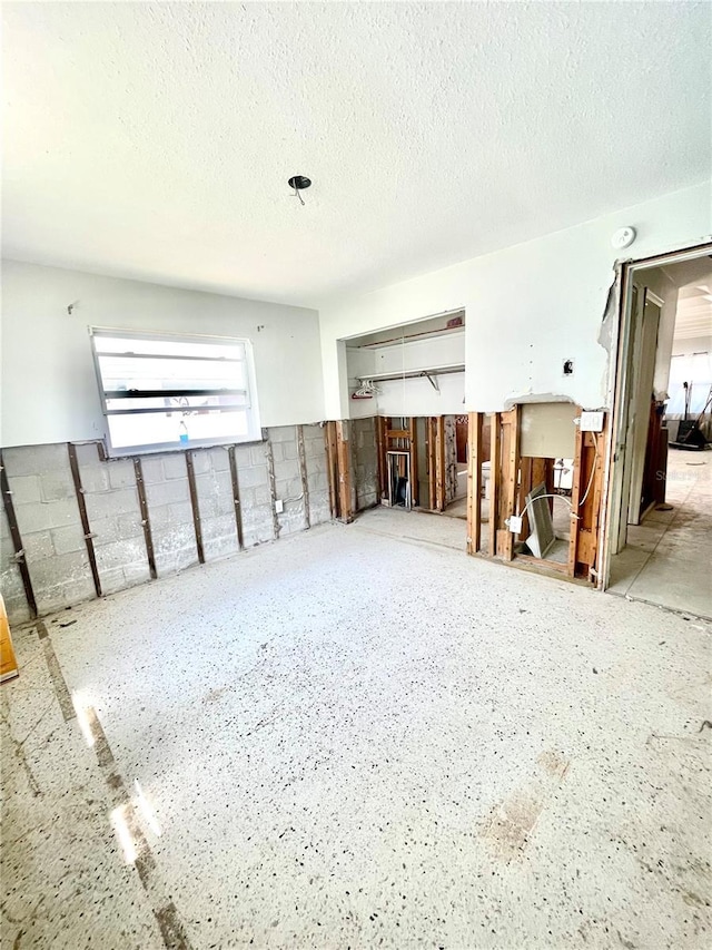 interior space with concrete block wall and a textured ceiling