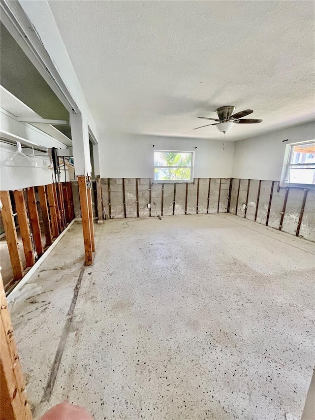 spare room with ceiling fan, a wealth of natural light, and a textured ceiling