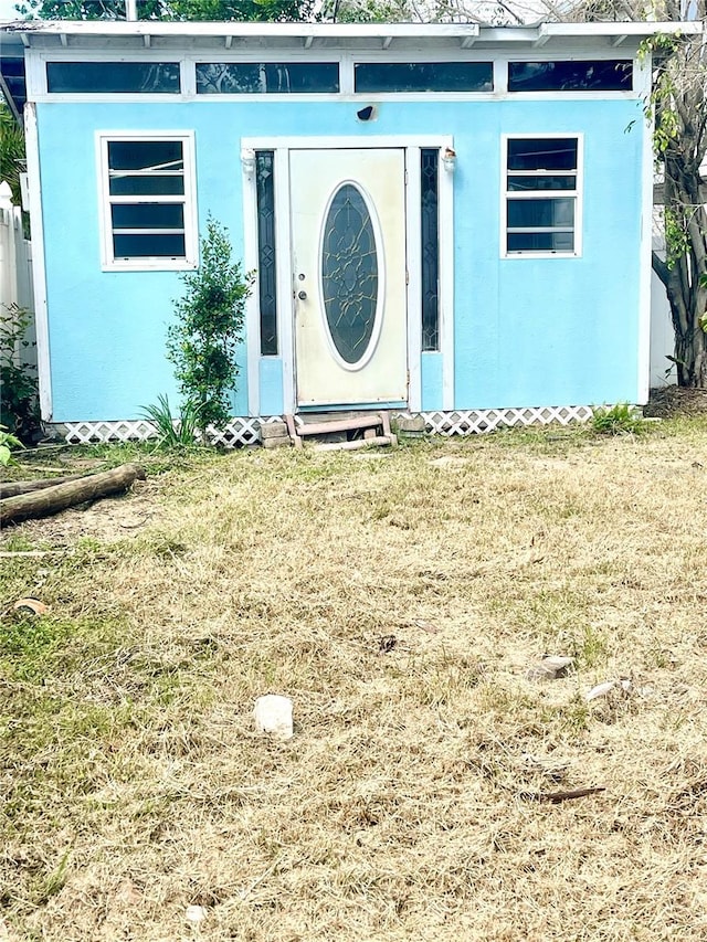 property entrance with a yard and stucco siding