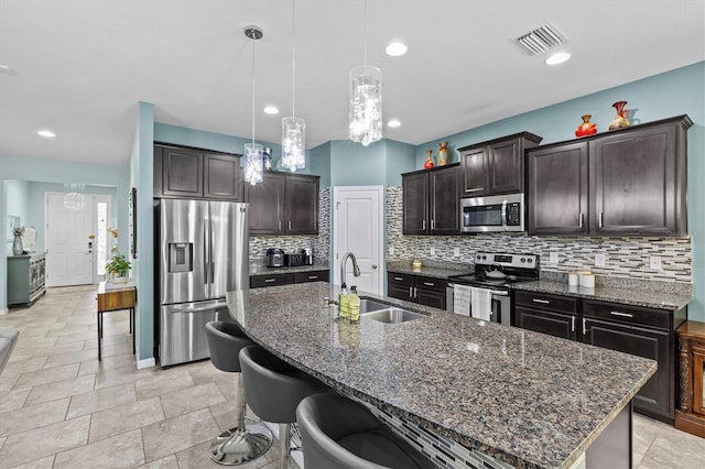 10514 Scenic Hollow Dr, Riverview, FL 33578 - kitchen featuring stainless steel appliances, a sink, decorative backsplash, a center island with sink, and a breakfast bar