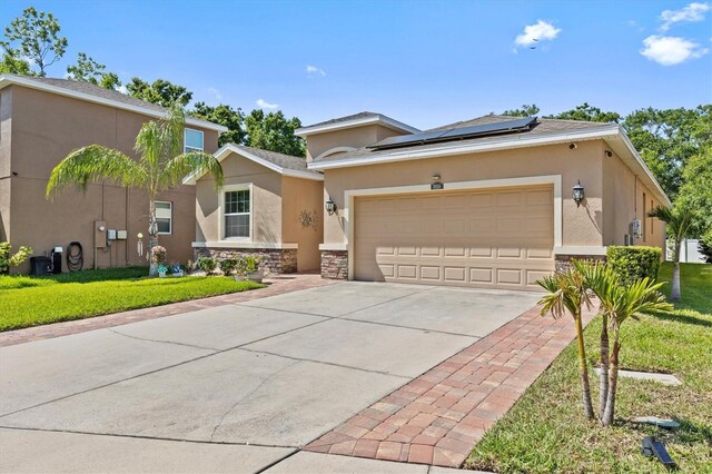 10514 Scenic Hollow Dr, Riverview, FL 33578 - view of front of home with stucco siding, roof mounted solar panels, driveway, stone siding, and an attached garage