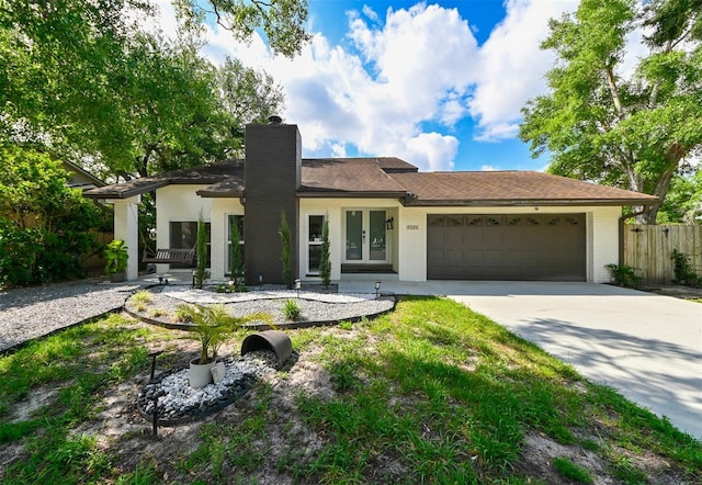 4520 Wescott Ln, Tampa, FL 33624 - ranch-style home with a chimney, fence, driveway, french doors, and a garage
