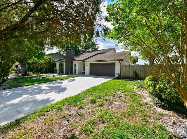 4520 Wescott Ln, Tampa, FL 33624 - view of front of home featuring a chimney, fence, driveway, and a garage