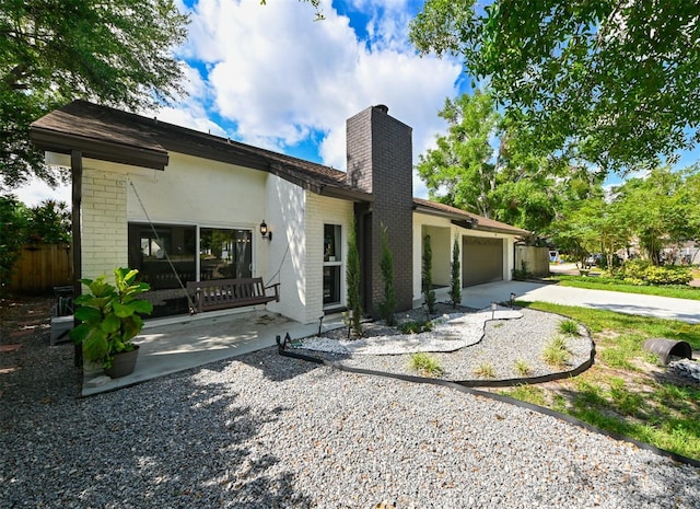 4520 Wescott Ln, Tampa, FL 33624 - rear view of house with concrete driveway, a chimney, brick siding, and a garage