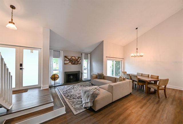 4520 Wescott Ln, Tampa, FL 33624 - living room featuring a fireplace with flush hearth, wood finished floors, a healthy amount of sunlight, and an inviting chandelier