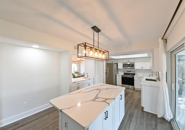 4520 Wescott Ln, Tampa, FL 33624 - kitchen featuring a center island, dark wood-style floors, decorative backsplash, light stone counters, and appliances with stainless steel finishes