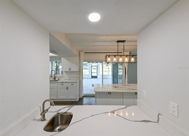 4520 Wescott Ln, Tampa, FL 33624 - kitchen with a sink, decorative light fixtures, light stone countertops, decorative backsplash, and white cabinetry