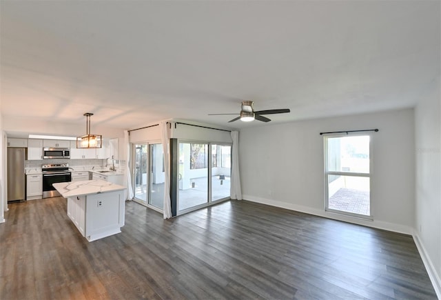 4520 Wescott Ln, Tampa, FL 33624 - unfurnished living room featuring baseboards, dark wood-style flooring, ceiling fan, and a healthy amount of sunlight