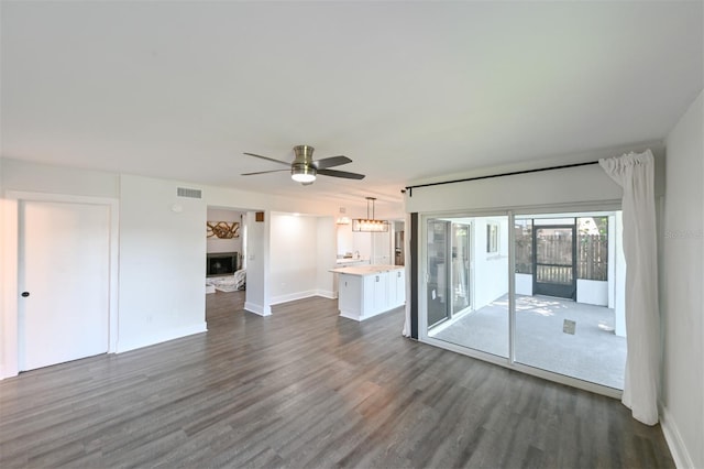 4520 Wescott Ln, Tampa, FL 33624 - unfurnished living room with dark wood finished floors, baseboards, visible vents, ceiling fan, and a fireplace
